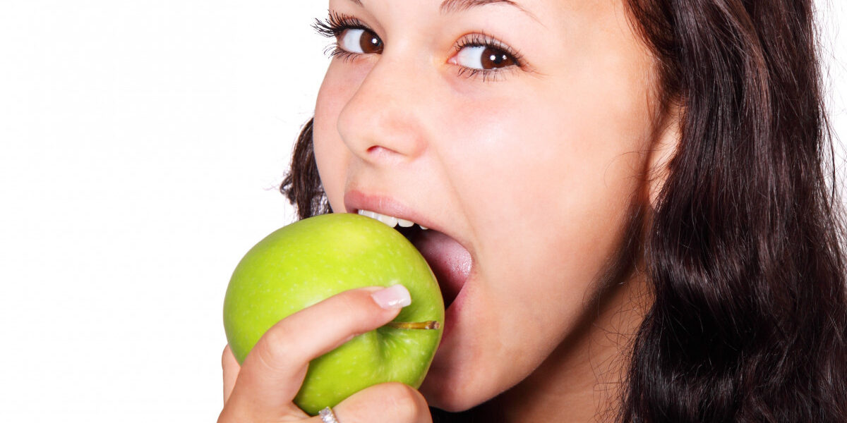 Una mujer con una manzana verde en la boca Descripción generada automáticamente con confianza media